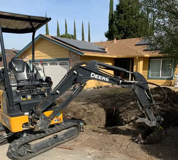 Excavator in residential yard for sewer repair in Antioch, CA.