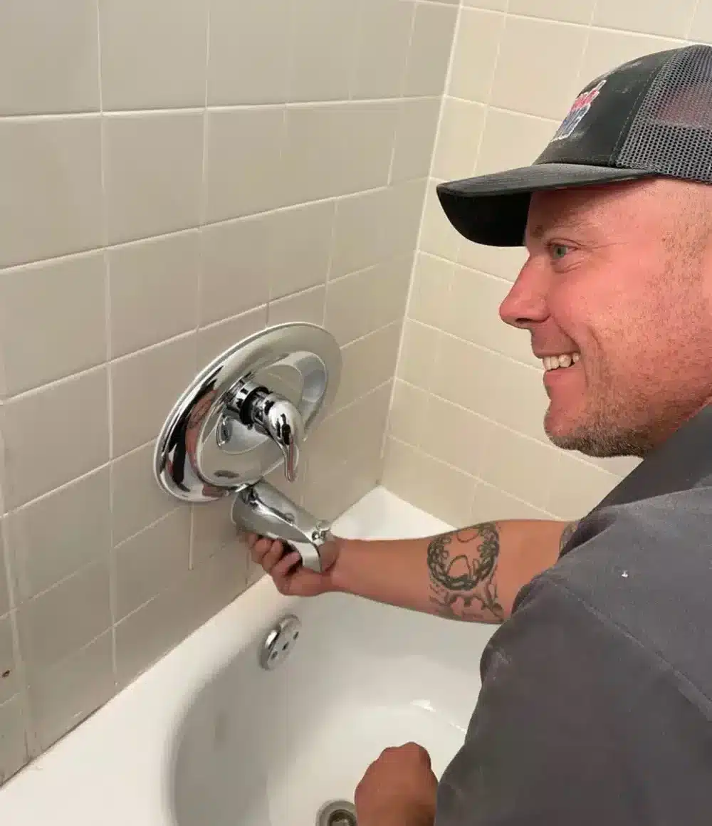 Tech smiling fixing new bathtub fixtures in residential home in Antioch, CA.