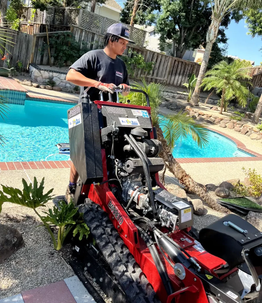 In Demand Plumbing tech in residential backyard with trencher in Antioch, CA.